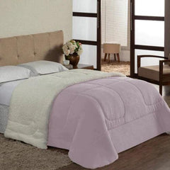 uma cama com um coberdrom sherpa dupla face branco e travesseiros azuis. O coberdrom tem um lado felpudo e outro liso.