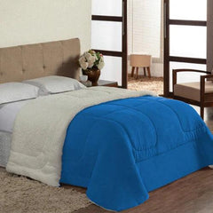 uma cama com um coberdrom sherpa dupla face branco e travesseiros azuis. O coberdrom tem um lado felpudo e outro liso.