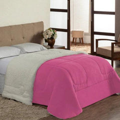 uma cama com um coberdrom sherpa dupla face branco e travesseiros azuis. O coberdrom tem um lado felpudo e outro liso.