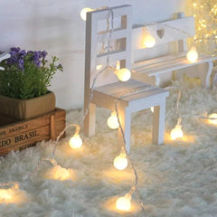 Um jardim florido com um caminho iluminado por um varal de luzes LED cordão