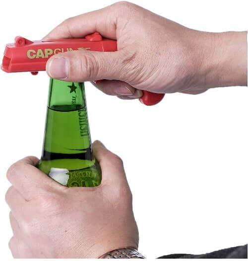  imagem de um abridor de garrafa atirador de tampas cap gun vermelho abrindo uma garrafa de cerveja e lançando a tampa