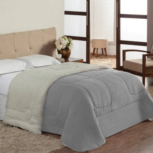  uma cama com um coberdrom sherpa dupla face branco e travesseiros azuis. O coberdrom tem um lado felpudo e outro liso.